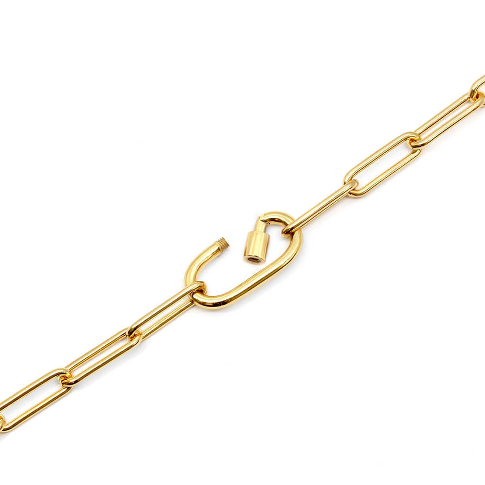 Photo featuring the Daily Charm Necklace in gold vermeil from Jet Set Candy. The necklace features long rectangular links with rounded corners and an inch-long carabiner charm clip that is shown open which allows for charms to be added. The necklace is shown on a diagonal on a white background.