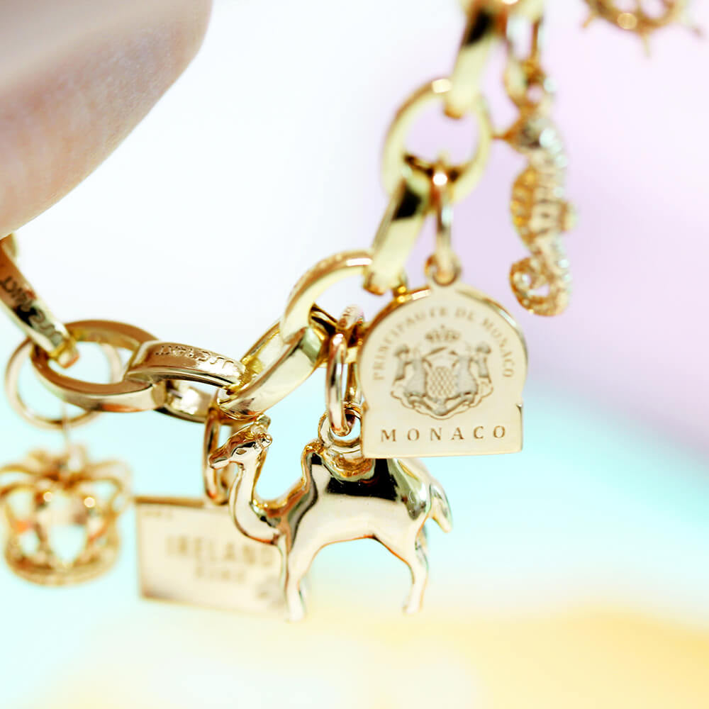 7 solid gold charms that are travel-themed including a 3D Eiffel Tower Charm and a solid yellow gold and white gold Trolley charm with moving wheels