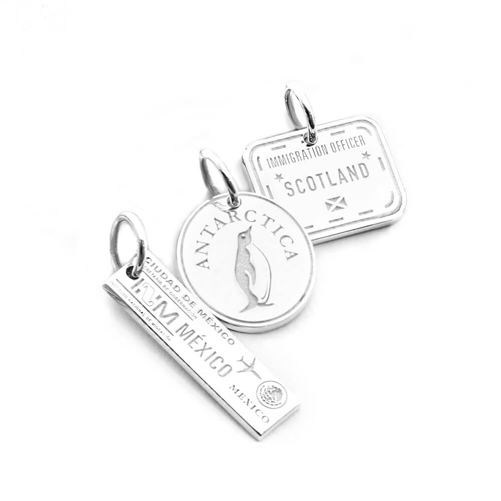 Bundle of three sterling silver passport stamp charms by Jet Set Candy, featuring various country-themed designs on a white background.