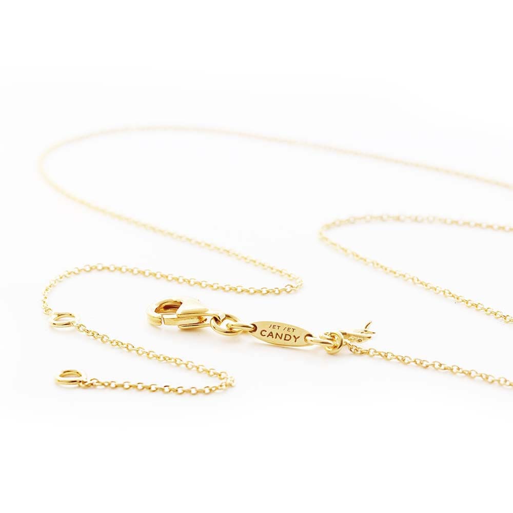 Gold charm necklace chain featuring a lobster clasp and an oval tag engraved with JET SET CANDY text.