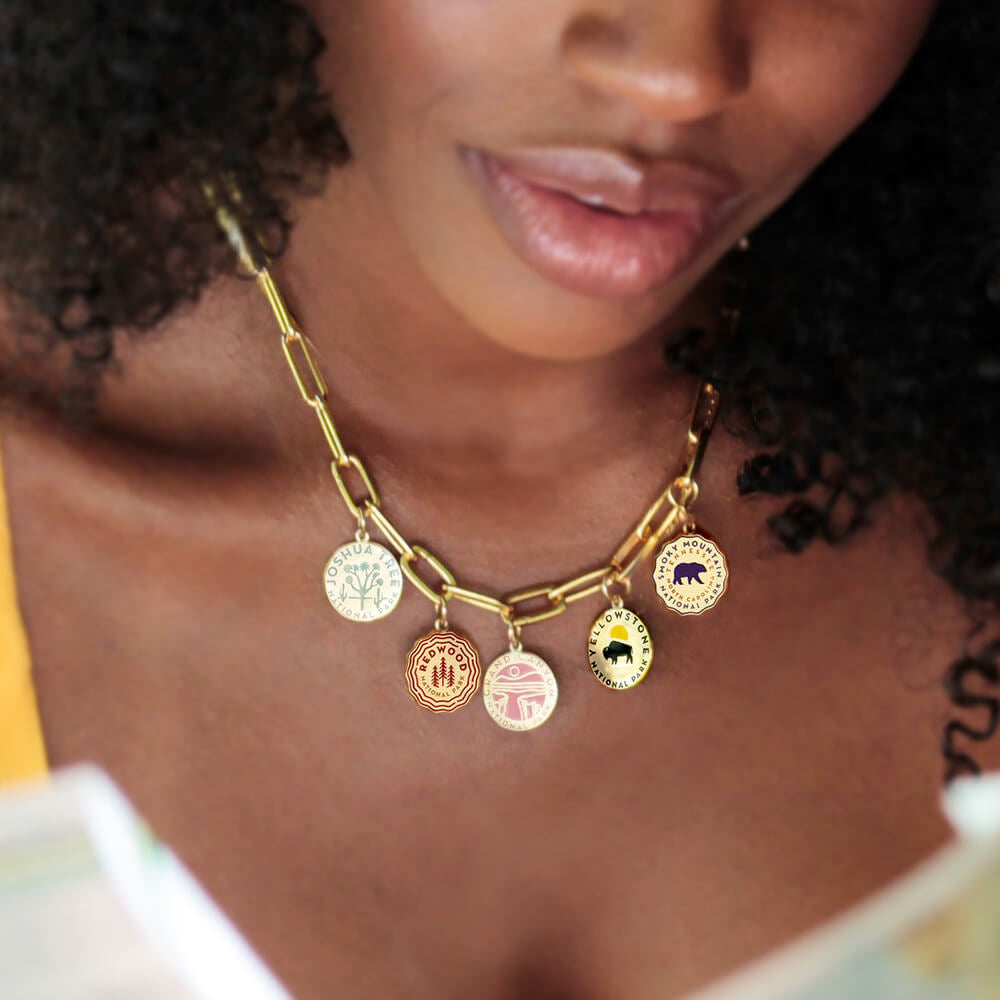 Gold vermeil clip necklace with opening clips and gold vermeil enamel charms representing national parks such as redwood, joshua tree, yellowstone, grand canyon, smoky mountain