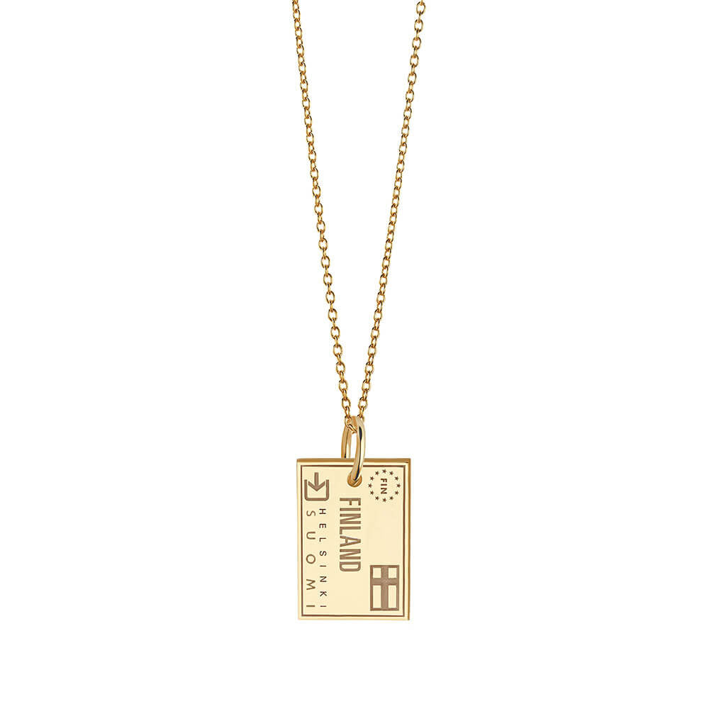 Gold charm necklace featuring Helsinki Finland passport stamp engraving with airplane icon, European Union stars, and Suomi text motif.