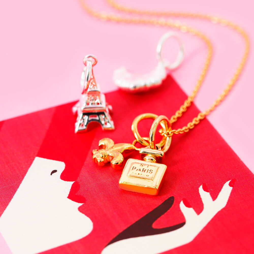 Gold Charm necklace featuring a Paris No 1 perfume bottle and fleur-de-lis, alongside a Sterling Silver Eiffel Tower.