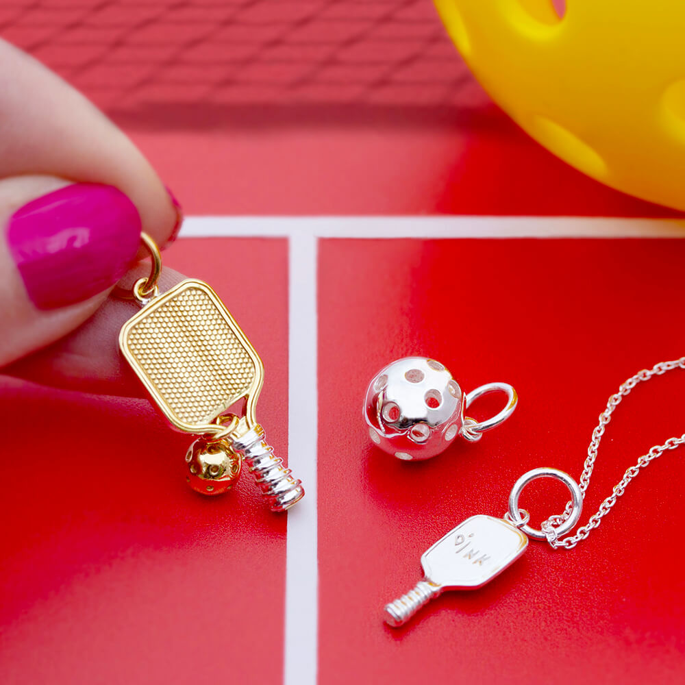 Two-tone charm and Sterling Silver charms featuring 3D pickleball paddles and balls with textured honeycomb and dink engravings.