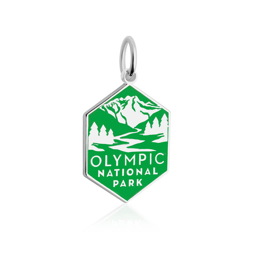 The image displays a hexagonal sterling silver charm with a green enamel background. The charm features white enamel illustrations of a mountain range, evergreen trees, and a winding river. Below the illustration, the text 