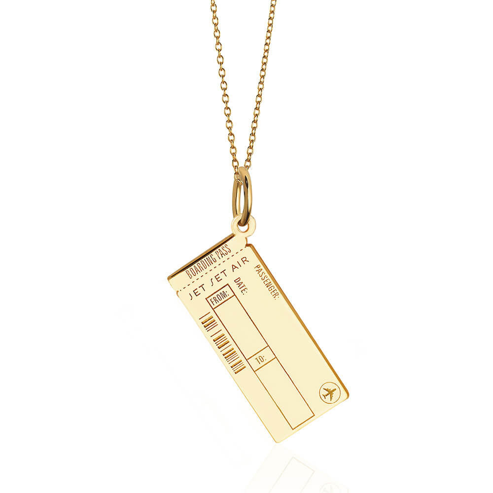 Photo of a gold vermeil Boarding Pass Charm hanging on a thin cable chain from JET SET CANDY shown on a white background. The charm is completely customizable with fields for engraving for Name, Date, and airport codes as well as allowing for back engraving at an additional cost of $15. It looks very similar to a real boarding pass and includes an airplane icon and fake engraved bar code.