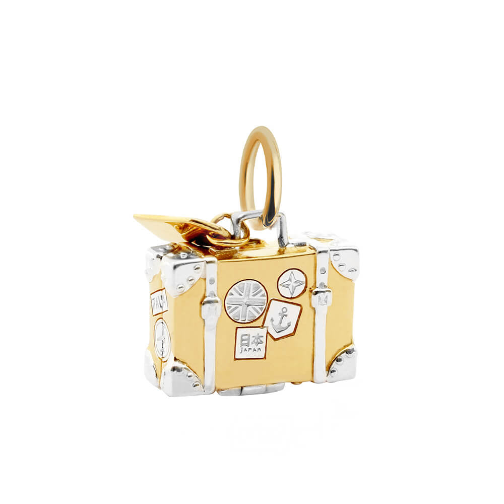 Image of a sterling silver and gold suitcase charm. The charm looks like a vintage suitcase and the body of the charm is silver and there are gold travel stickers in different shapes that say “Paris” “India” and “NY”. There are also corner and strap details in gold. There is a tiny tag that says “Flight Number” hanging from the handle. The suitcase charm is from Jet Set Candy and it opens to reveal little chain straps. Approximate dimensions: 16.9 mm x 13.4 mm