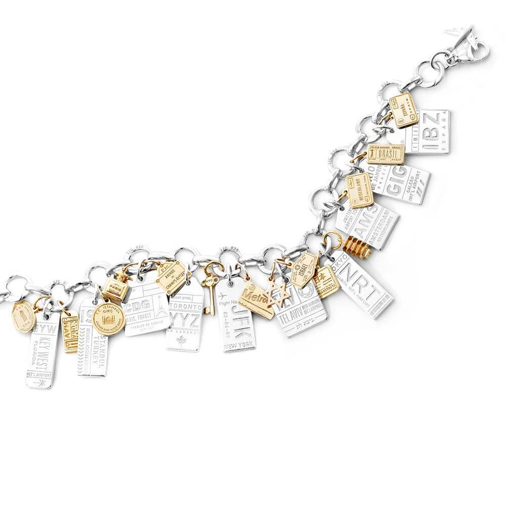 Travel charm bracelet featuring sterling silver Luggage Tag Charms with airport codes for a variety of destinations from Jet Set Candy including souvenir charms for Key West, Istanbul, Paris, Toronto, New York, Tel Aviv, Tokyo, Amsterdam, Rio, and Ibiza. Mini solid gold travel charms are also shown on this charm bracelet which is shown on a white background 