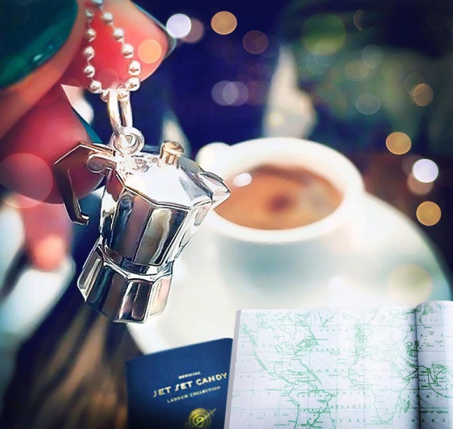 Silver Italy espresso coffee pot charm by Jet Set Candy, held by model on a blurred background.