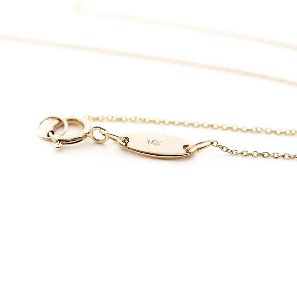 Solid gold cable chain shown in a snaking position on a white background with a focus on the small  back tag that has “14k” engraved into it. The chain is made by Jet Set Candy.