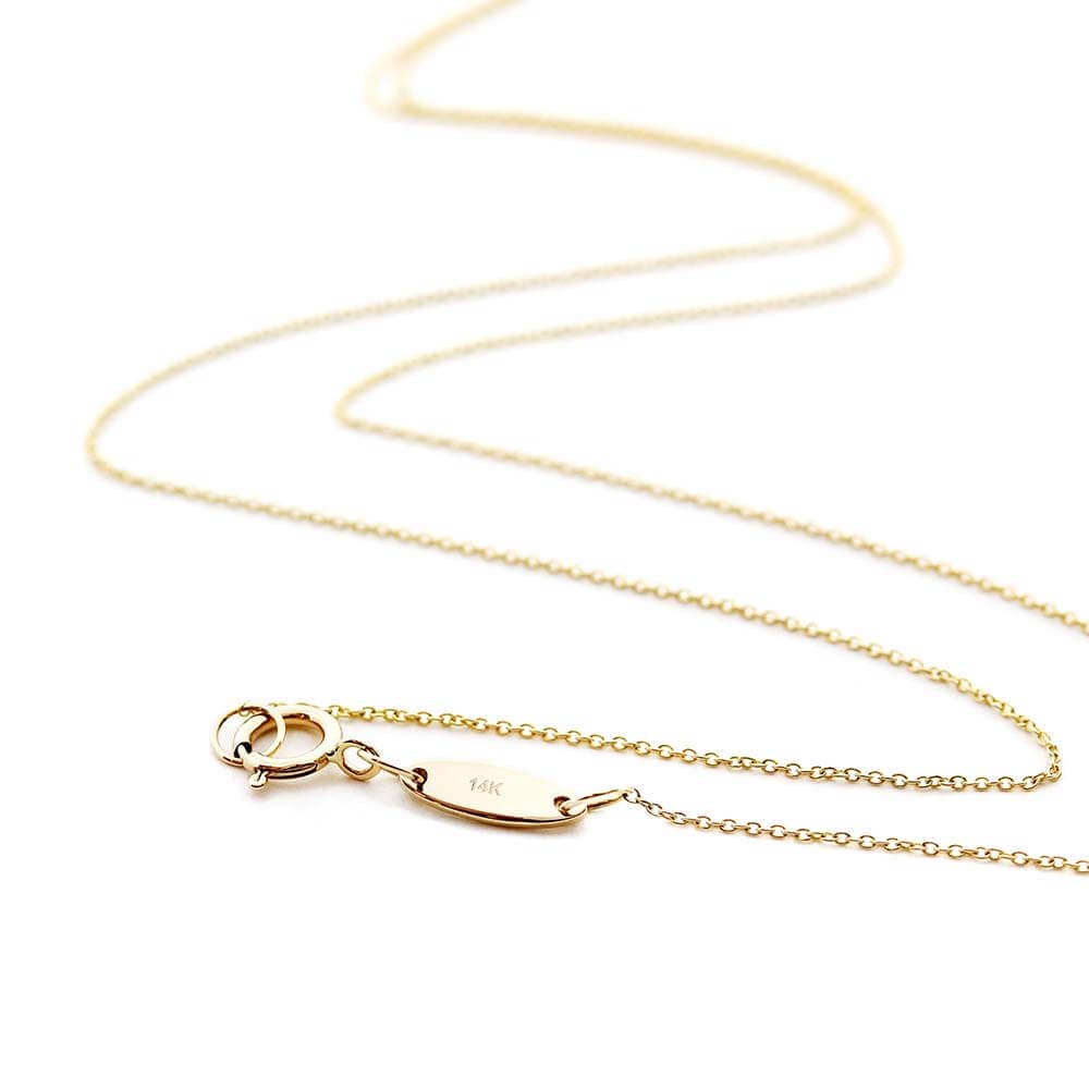 Solid gold cable chain shown in a snaking position on a white background with a focus on the small  back tag that has “14k” engraved into it. The chain is made by Jet Set Candy.